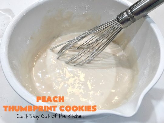 Peach Thumbprint Cookies | these fantastic little #cookies are terrific for #holiday #baking & #ChristmasCookieExchanges. They're filled with #peach jam & iced with a heavenly vanilla powdered sugar icing. #dessert #holiday #HolidayDessert ChristmasDessert #ChristmasCookie #PeachDessert #ThumbprintCookie