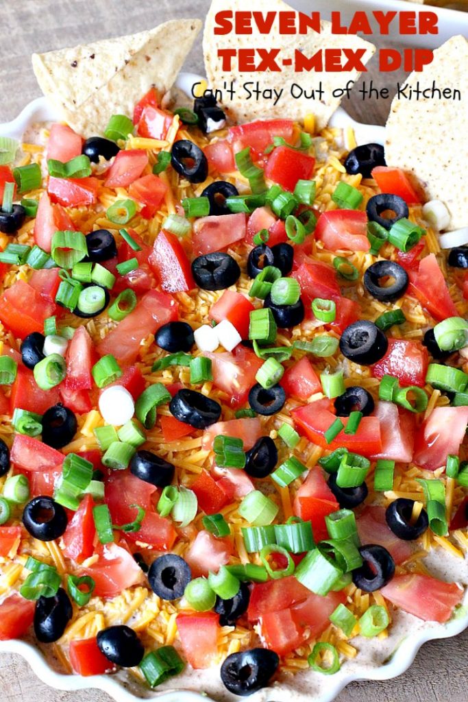 Seven Layer Tex-Mex Dip | Can't Stay Out of the Kitchen | this awesome #TexMex #dip is out of this world. It's terrific for any kind of company or #holiday party. We like it for #tailgating parties & potlucks. Also great for summer #holidays like #FourthOfJuly. #GlutenFree #Mexican #TexMexDip #LayeredMexicanDip #RefriedBeans #Jalapenos #Olives #CheddarCheese #Guacamole #TortillaChips #tomatoes #Avocados #SevenLayerTexMexDip #appetizer #TexMexAppetizer